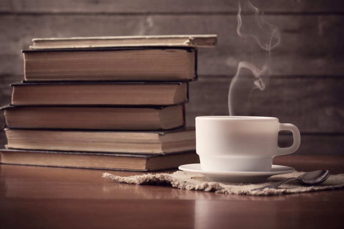 old books on wooden background with cup of coffee